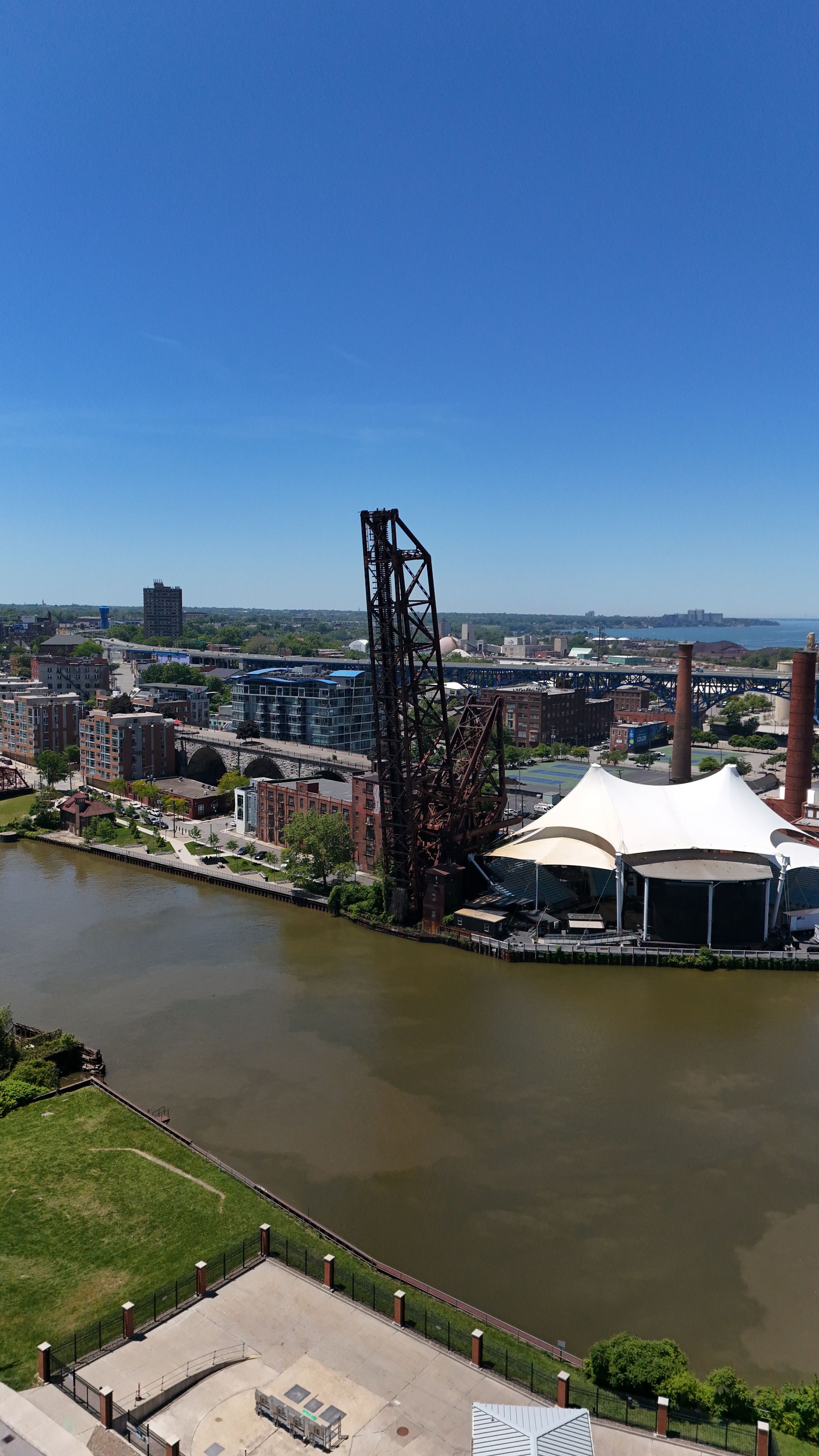 Aerial photograph of the Cuyahoga River with a historic lift bridge and the riverfront pavilion, Cleveland skyline beyond — Stratum Aerial Media